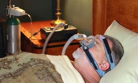 An older man sleeps with a CPAP mask in bed