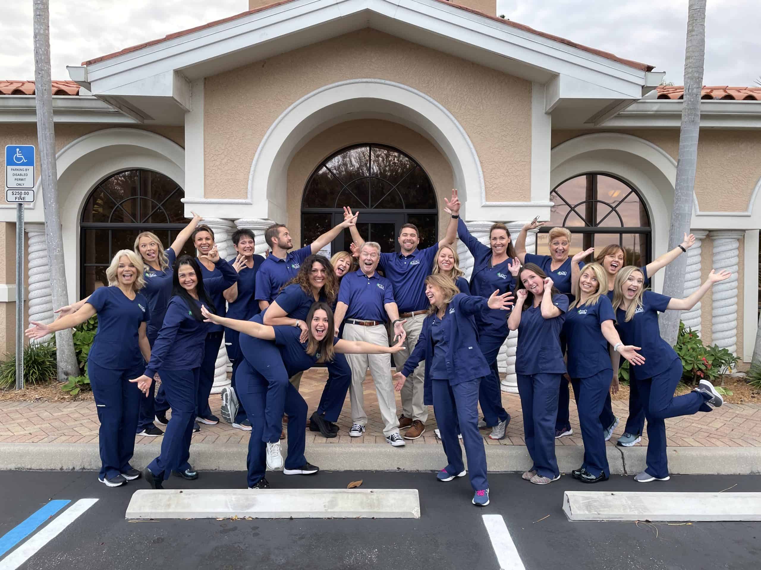 Cape Dental Care staff smiling as they do a welcoming pose in front of the Cape Coral location