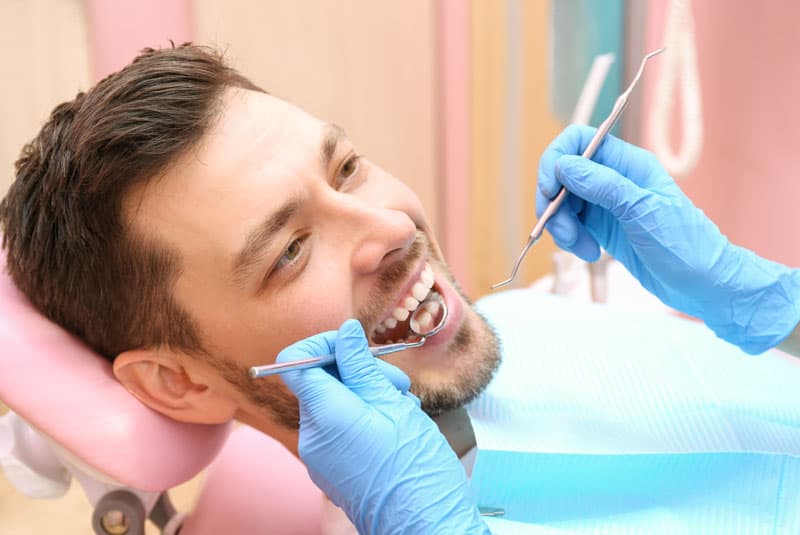Patient smiling while dentist performs post-periodontal treatment checkup