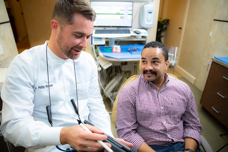 Dr. Phillip Kraver shows a patient his scan during a dental implant consultation to determine a personalized treatment plan