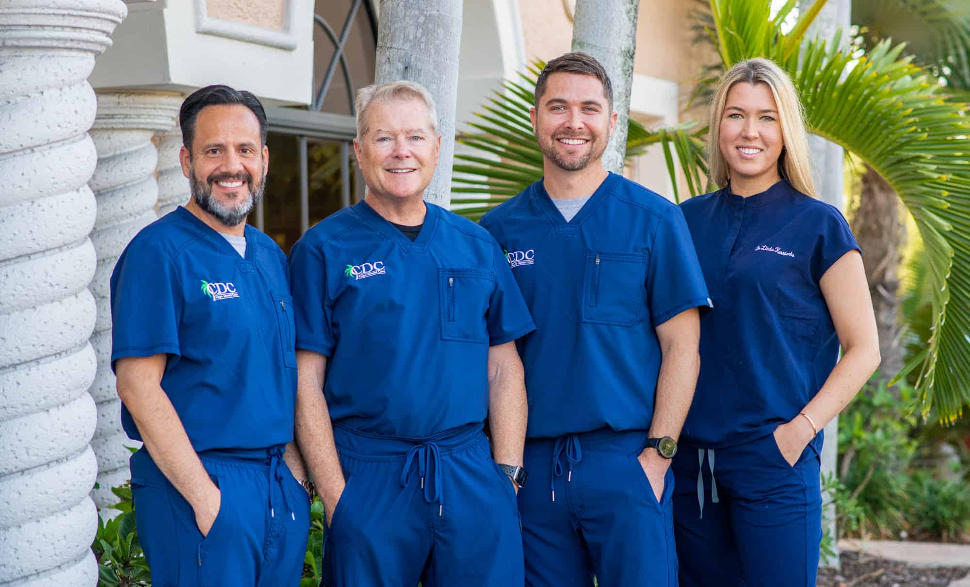 Cape Dental Care's four doctors from left to right Dr. Mario Romero (left), Dr. Mark Kraver (left middle), Dr. Phillip Kraver (right middle), and Dr. Linda Kornienko (right) smiling as they pose together in front of their office